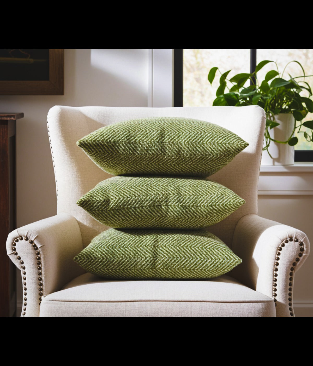 “Stacked light green chevron-pattern handmade luxury pillows on an ivory armchair – Upland Collection by Sundara Casa.”
