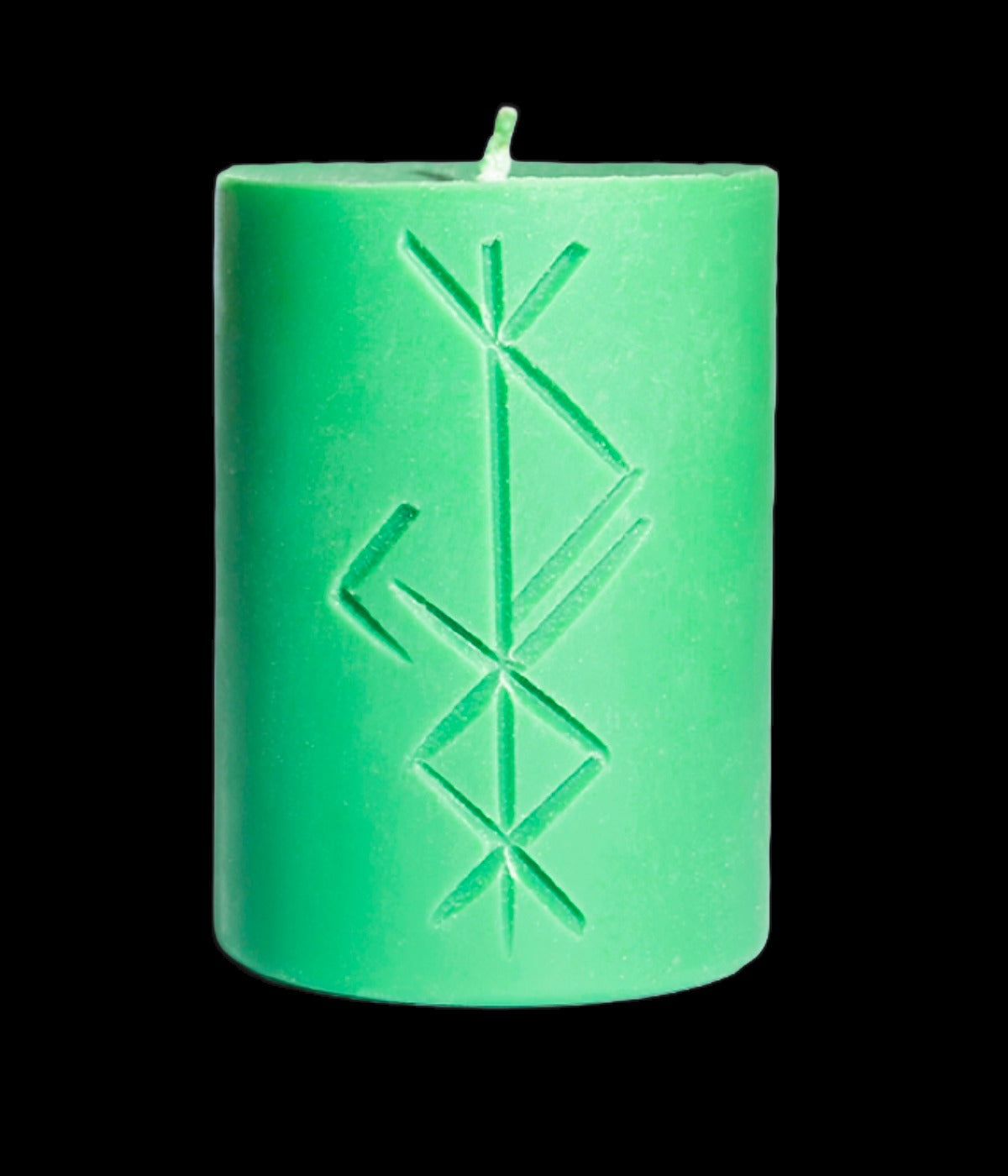 Green rune carved candle standing upright on a black background
